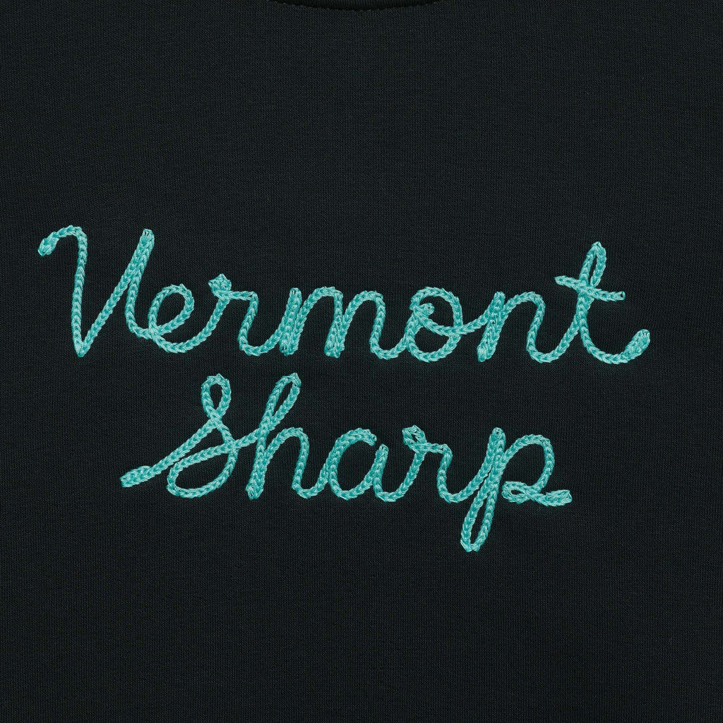 The New Duds Vermont Sharp Chainstitched Crewneck features Vermont Sharp chain-stitched in light blue cursive on a dark fabric background.
