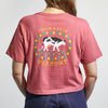 A person wearing the Cabot x Always With Honor Cropped T-shirt by New Duds—a pink, boxy fit shirt with a pixelated cow graphic, "Fresh From Vermont" on the back, and yellow text on the left sleeve.