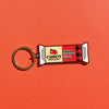 The WizardPins Seriously Sharp Charm Keychain, shaped like a cheese bar with “Cabot Creamery Vermont Seriously Sharp” label, stands out on a bold orange background.