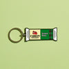 The Vermont Sharp Charm Keychain by WizardPins, inspired by Cabot Creamery's sharp cheddar packaging and logo, is shown on a light green background with its distinctive green and white design.