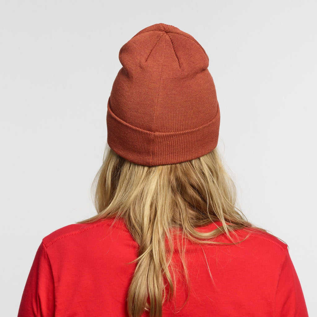 A person with long blonde hair is seen from behind, wearing a red New Duds Life is Cheddar in Vermont Patch Beanie and a matching red shirt, set against a plain light gray background.