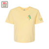 The Cabot x Always With Honor Crop T-shirt by New Duds is a pale yellow, garment-dyed tee with a small flower and “YAY!” on the left chest, CARE logo patch on the left sleeve, and a badge stating “10% OF SALES Donated.”.