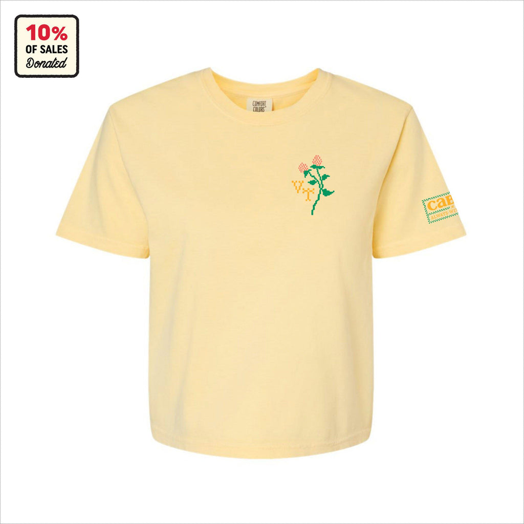 The New Duds Cabot x Always With Honor Crop T-shirt is a light yellow heavyweight boxy tee featuring a small flower graphic on the left chest, a care patch on the sleeve, and Vermont-inspired details. 10% of sales are donated.