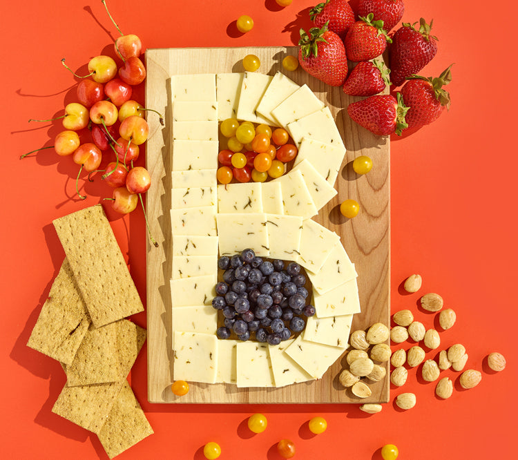 A cheese board in the shape of a B on an orange background.