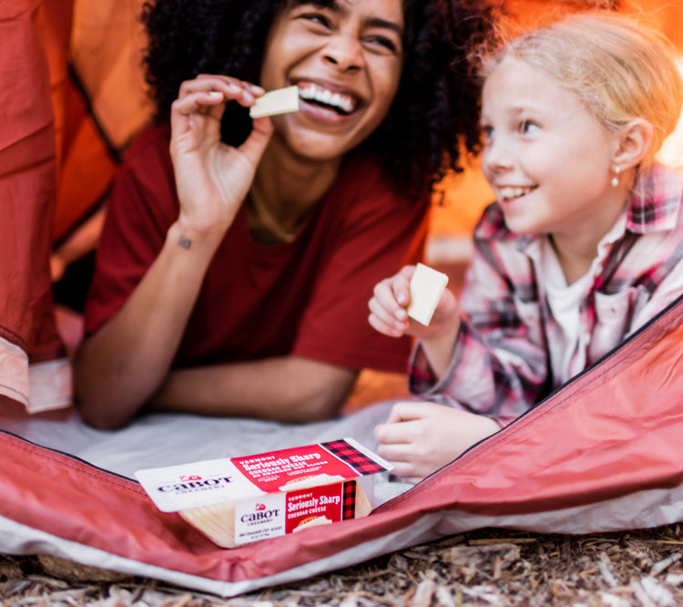 Mother and daughter eating Cabot cheese in a tent
