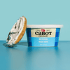 A tub of Cabot Creamery Plain Cream Cheese next to a bagel half topped with breakfast cream cheese.
