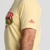 A person shown from the side wearing the New Duds “Life is Butter in Vermont” T-shirt, a light yellow shirt featuring Cabot Creamery with a red cow logo printed on the sleeve.