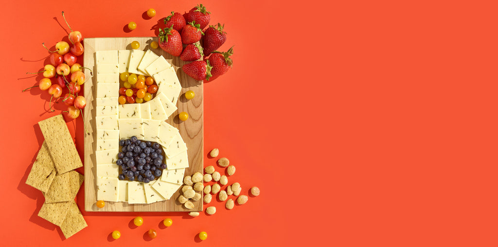 A cheese board in the shape of a B on an orange background.