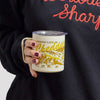 A person holds a Where Life is Cheddar Insulated Mug featuring a mountain landscape and farm illustration with the text, Where Life is Cheddar.