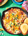 shakshukah dish in a cast iron skillet with toasted bread on a green background