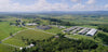 Ariel shot of barn in Vermont with wind turbine, green grass and lots of trees.